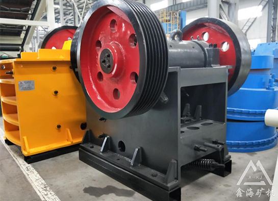 What is the function of the flywheel in the jaw crusher